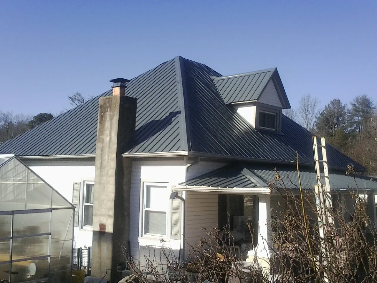 Dark blue standing seam metal roof on a white farmhouse with dormer — Slate & Tile Roof Repair by Roofing Brothers in Danvers