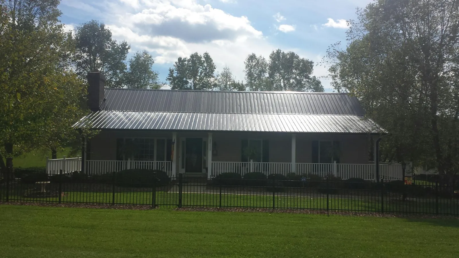 Gray metal roof on a brick ranch with a full width front porch — Gutter Guard Installation work by our crew in Danvers