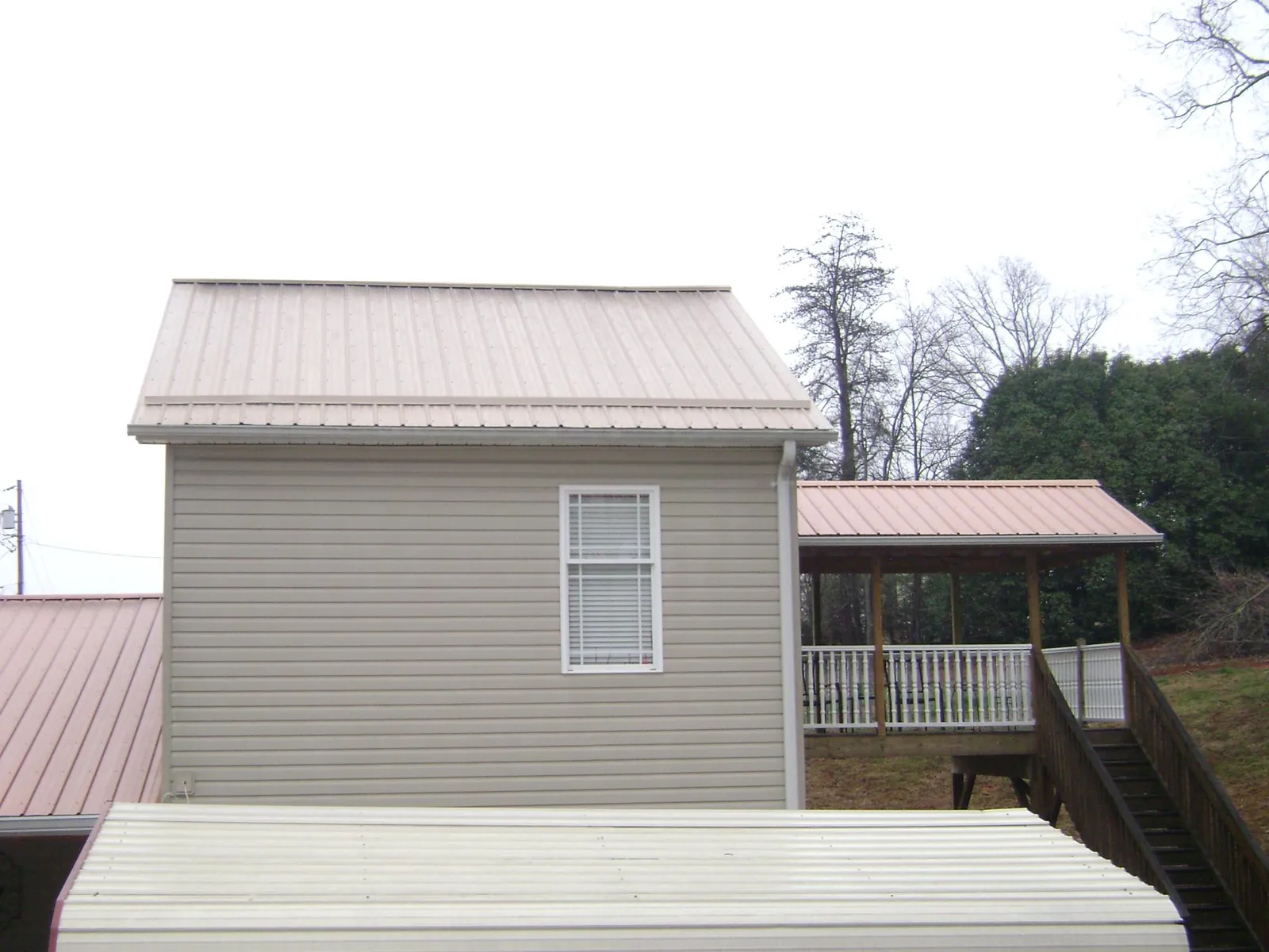 Tan metal roofs on a two story addition and attached porch, from a Roof Replacement job in Danvers